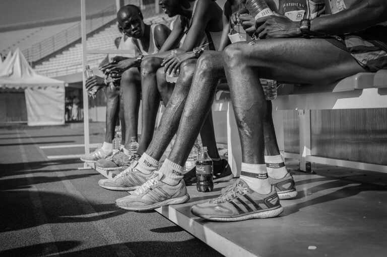 a group of professional runners sitting down on the bleachers_living in kigali